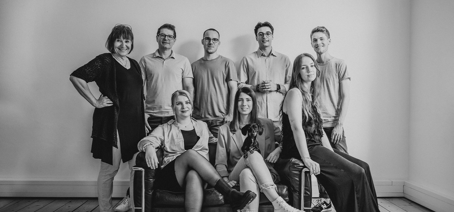 Das Team von Kokollektiv posiert für ein Gruppenfoto, wobei ein Teil hinter einem Sofa steht und ein Teil darauf sitzt.